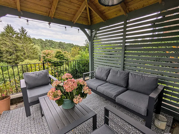 Furniture inside pergola with a view out over the hills